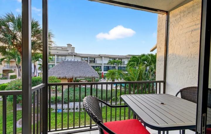 Screened lanai overlooking palms and the community pool at the Marco Island long term rental